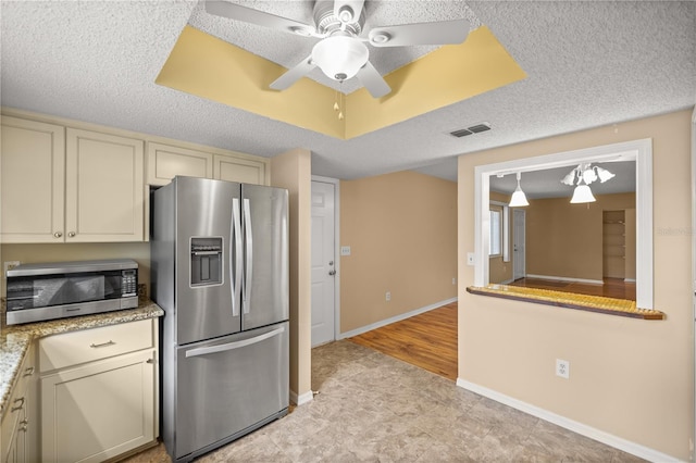 kitchen with light tile patterned floors, stainless steel appliances, cream cabinets, and a textured ceiling