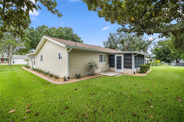 rear view of house featuring a lawn and a sunroom