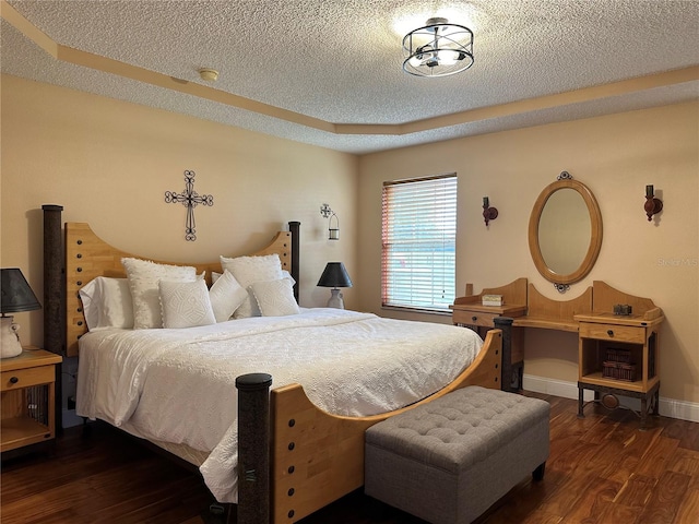 bedroom featuring a textured ceiling, a raised ceiling, and dark wood-type flooring