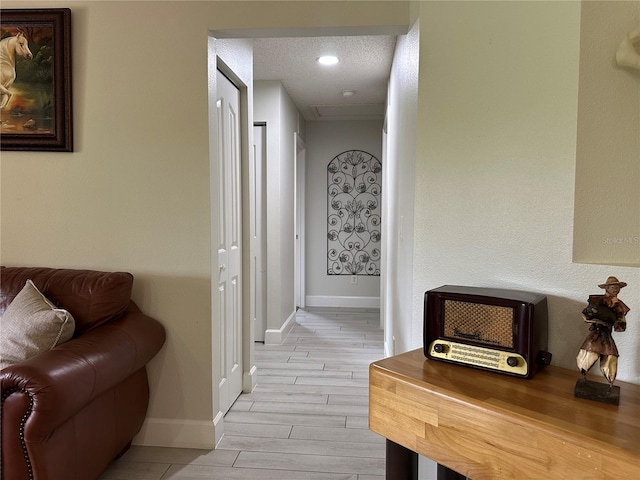 corridor featuring a textured ceiling and light hardwood / wood-style flooring