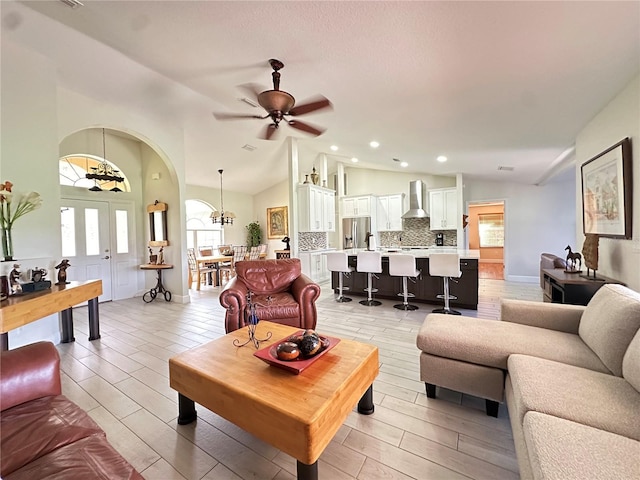 living room with ceiling fan with notable chandelier, a wealth of natural light, and lofted ceiling