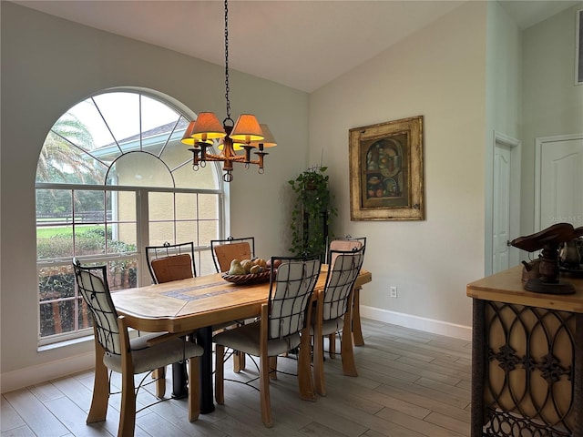 dining space with light wood-type flooring, lofted ceiling, and a chandelier