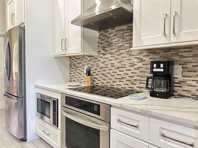 kitchen featuring backsplash, stainless steel appliances, white cabinetry, and wall chimney exhaust hood