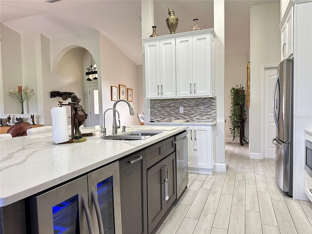 kitchen with white cabinets, sink, wine cooler, decorative backsplash, and appliances with stainless steel finishes