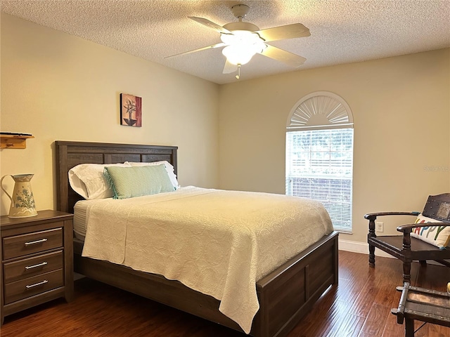 bedroom with a textured ceiling, ceiling fan, and dark hardwood / wood-style floors