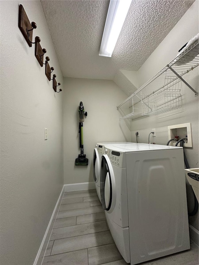 laundry area featuring washing machine and dryer, a textured ceiling, and light hardwood / wood-style flooring