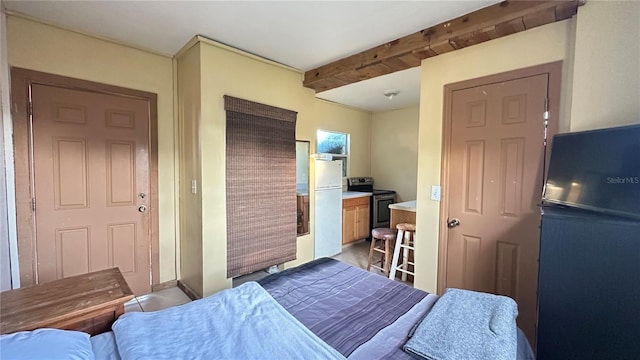 bedroom featuring beamed ceiling, fridge, and white fridge