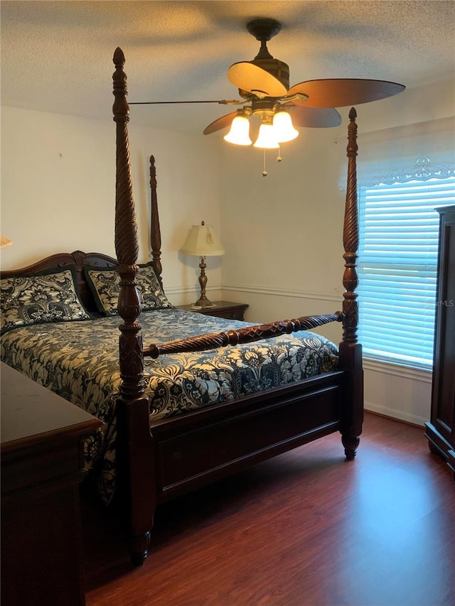 bedroom featuring ceiling fan, dark wood-type flooring, and a textured ceiling