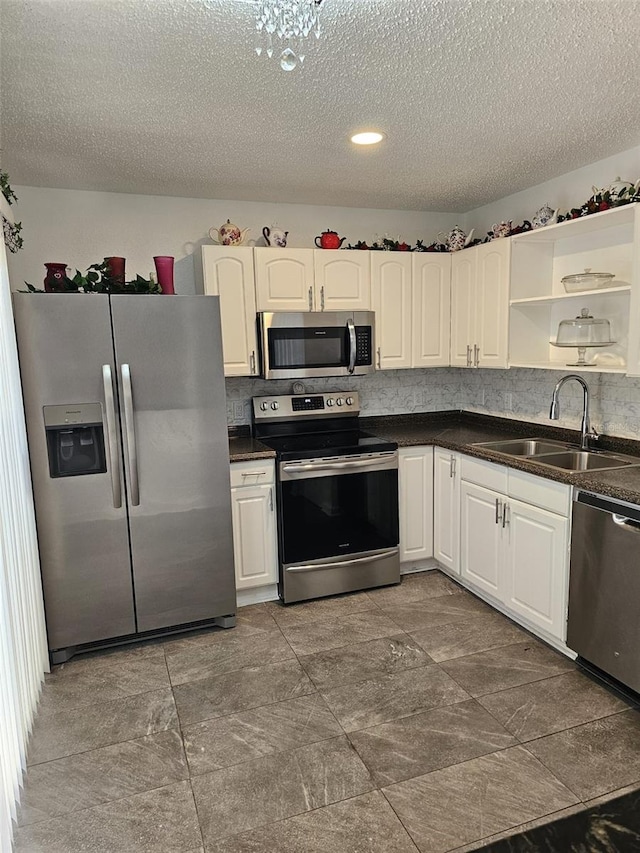 kitchen with white cabinets, a textured ceiling, appliances with stainless steel finishes, and sink