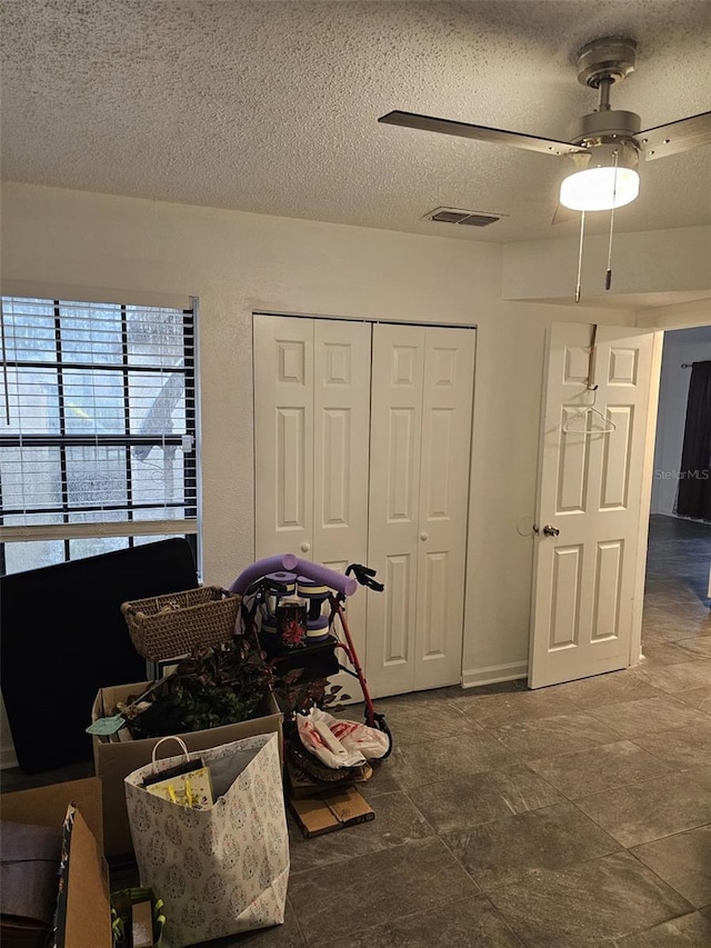 tiled bedroom with a closet, ceiling fan, and a textured ceiling