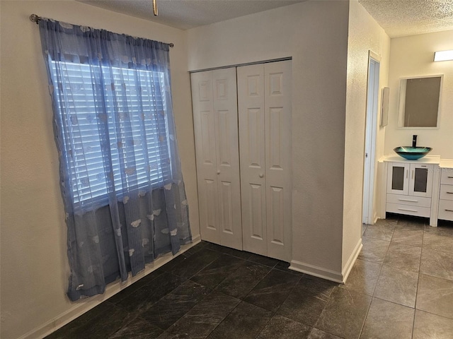 unfurnished bedroom featuring a textured ceiling, sink, and a closet