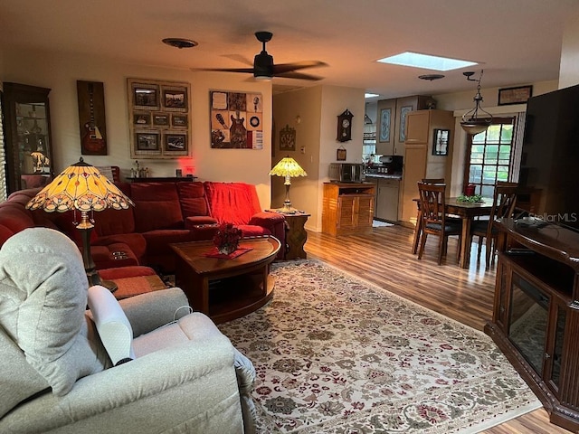 living room with hardwood / wood-style flooring, a skylight, and ceiling fan