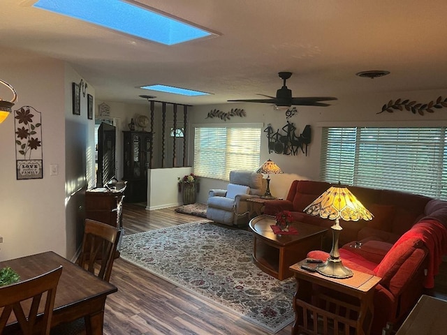 living room with ceiling fan, hardwood / wood-style flooring, and a skylight