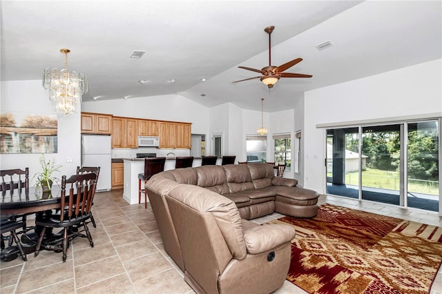 living area with ceiling fan with notable chandelier, high vaulted ceiling, light tile patterned floors, and visible vents