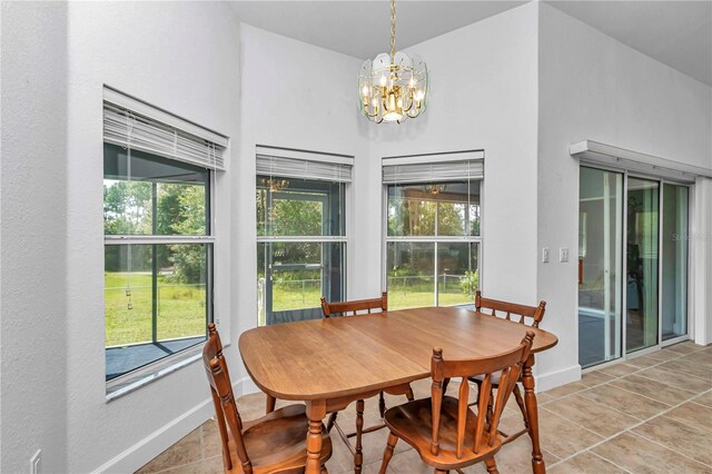 tiled dining space featuring a wealth of natural light, a high ceiling, and a chandelier