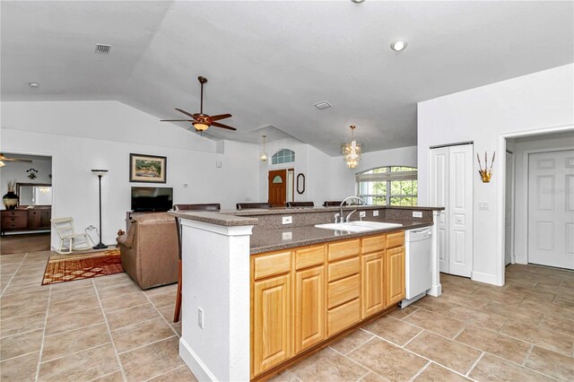 kitchen with sink, lofted ceiling, ceiling fan with notable chandelier, and a kitchen island with sink