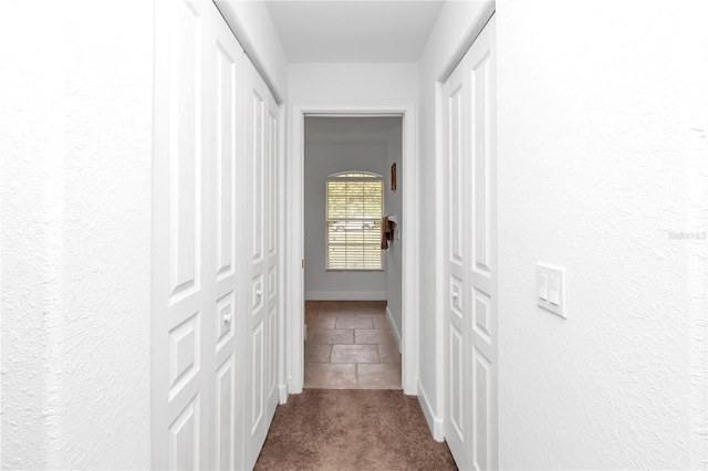 hallway featuring carpet flooring and baseboards