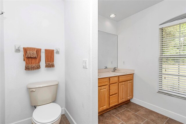 full bath with double vanity, toilet, a sink, baseboards, and tile patterned floors