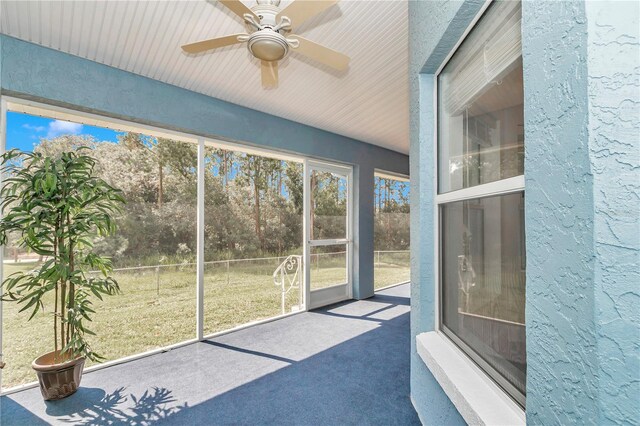 unfurnished sunroom with ceiling fan