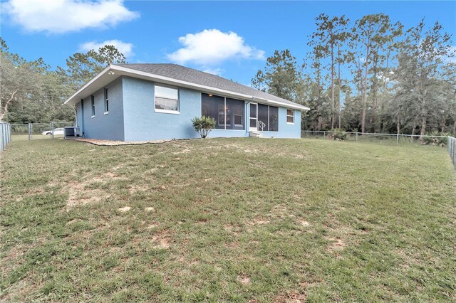 rear view of property with a sunroom, a fenced backyard, a lawn, and stucco siding