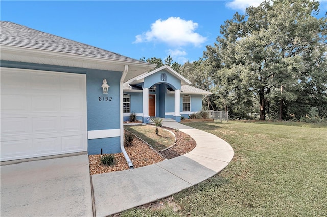 view of front of home with stucco siding, roof with shingles, an attached garage, fence, and a front yard