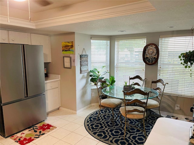 kitchen with stainless steel fridge, a textured ceiling, a wealth of natural light, and white cabinets