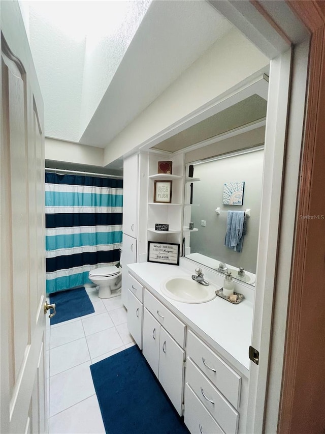 bathroom with tile patterned floors, a shower with shower curtain, toilet, and vanity