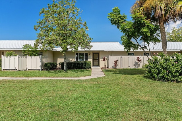 ranch-style home with metal roof, fence, a front lawn, and stucco siding