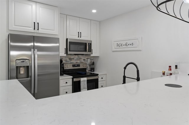 kitchen with stainless steel appliances, decorative backsplash, sink, light stone countertops, and white cabinets