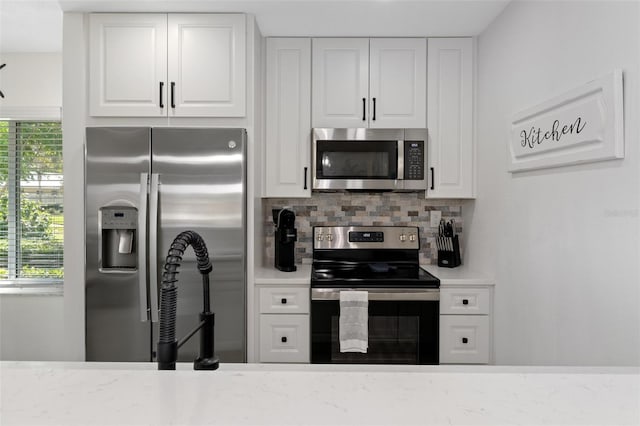 kitchen with white cabinets, appliances with stainless steel finishes, decorative backsplash, and light countertops