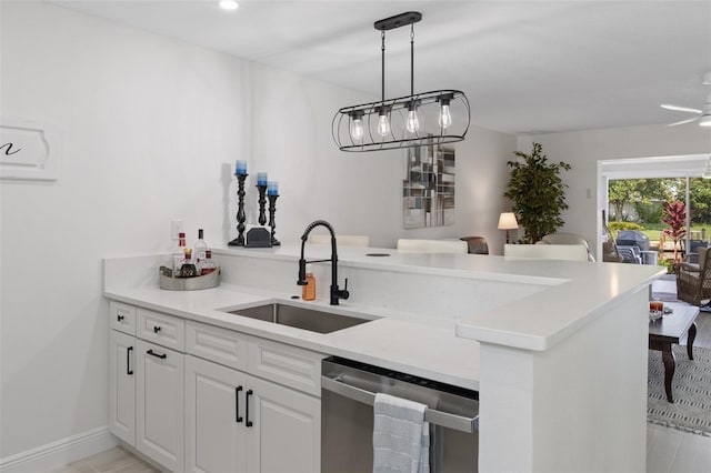 kitchen with stainless steel dishwasher, white cabinets, light stone counters, sink, and kitchen peninsula