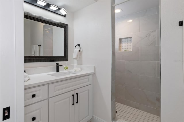 bathroom with a tile shower and vanity