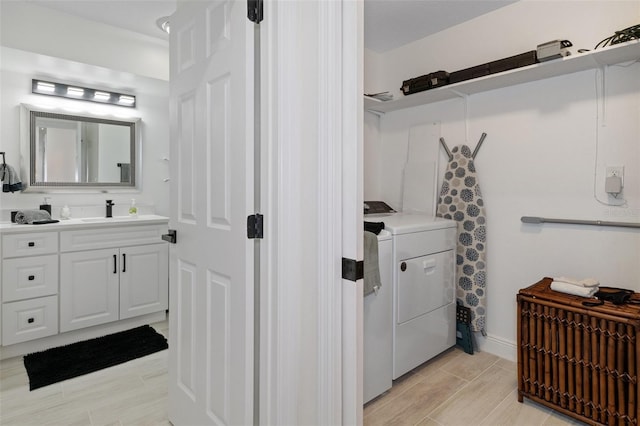 clothes washing area with wood finish floors, laundry area, a sink, and washer and clothes dryer