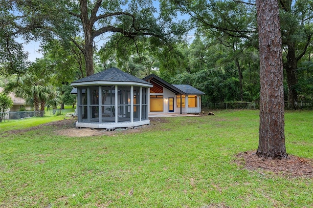 rear view of house with a sunroom and a yard