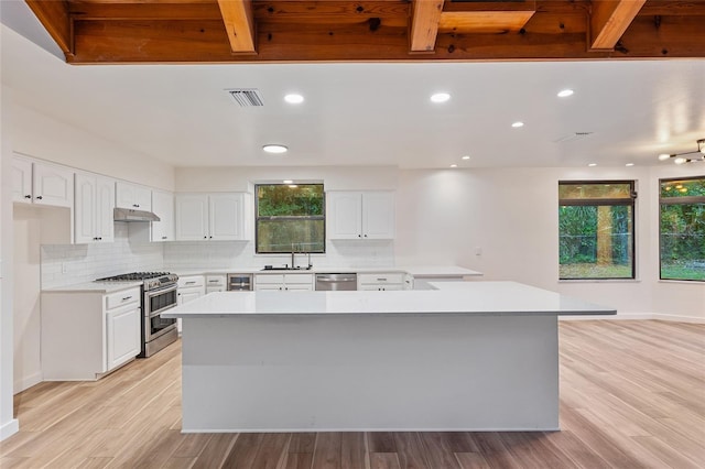 kitchen featuring appliances with stainless steel finishes, light hardwood / wood-style floors, white cabinets, and a healthy amount of sunlight