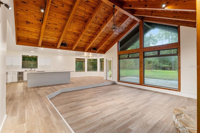 unfurnished living room with beamed ceiling, high vaulted ceiling, light hardwood / wood-style floors, and wooden ceiling