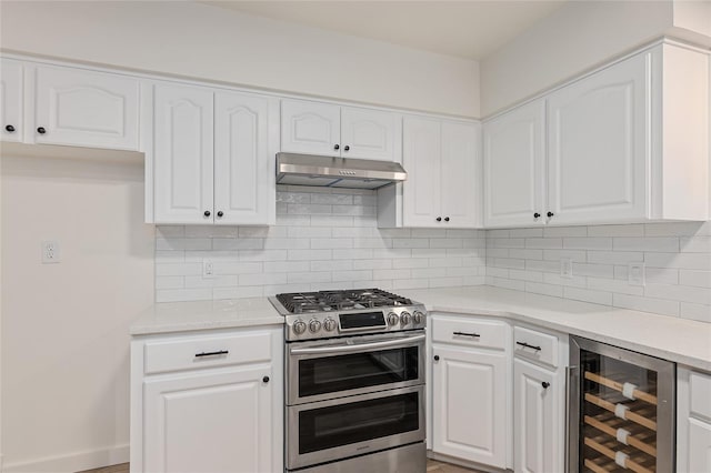 kitchen with backsplash, range hood, beverage cooler, stove, and white cabinets