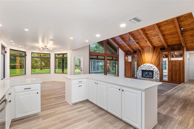 kitchen with vaulted ceiling with beams, a fireplace, light hardwood / wood-style floors, and wooden ceiling