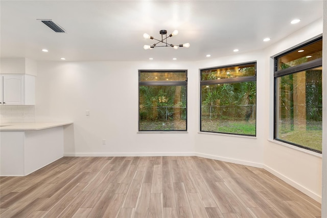 unfurnished dining area with light hardwood / wood-style floors and a notable chandelier