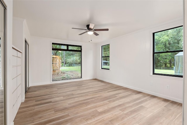 empty room with a wealth of natural light, ornamental molding, light hardwood / wood-style floors, and ceiling fan