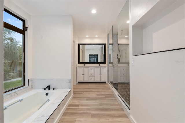 bathroom with separate shower and tub, vanity, and wood-type flooring