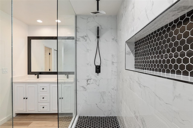 bathroom with tiled shower, hardwood / wood-style flooring, and vanity