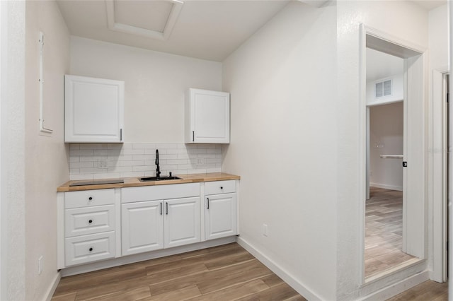 kitchen featuring sink, decorative backsplash, light wood-type flooring, and butcher block counters