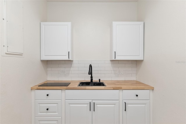 kitchen with wooden counters, sink, decorative backsplash, and white cabinets