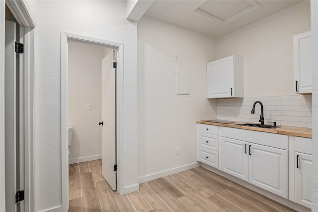 kitchen with sink, decorative backsplash, light hardwood / wood-style flooring, and white cabinetry