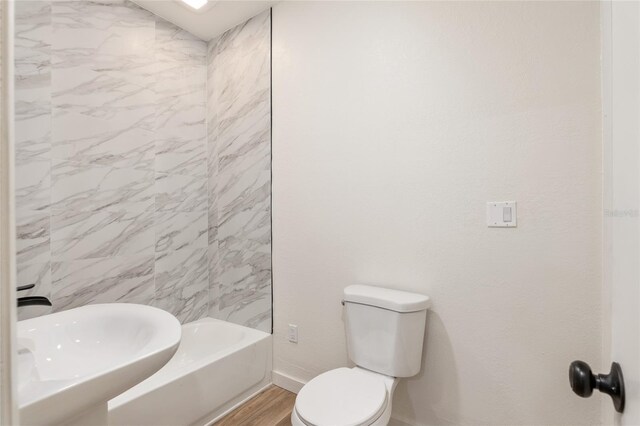 full bathroom featuring sink, wood-type flooring, toilet, and tiled shower / bath