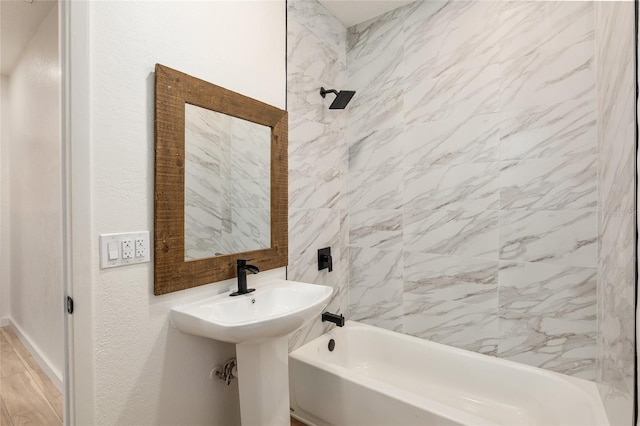 bathroom featuring wood-type flooring and tiled shower / bath