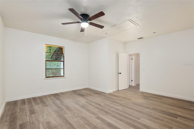 spare room featuring ceiling fan, light wood-type flooring, and a textured ceiling