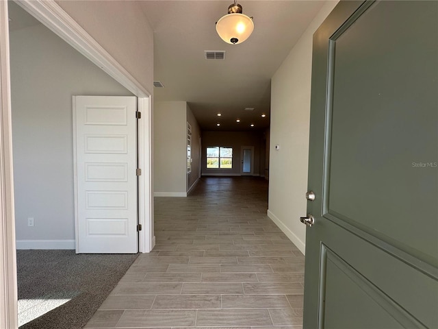 hallway with baseboards, wood tiled floor, and visible vents