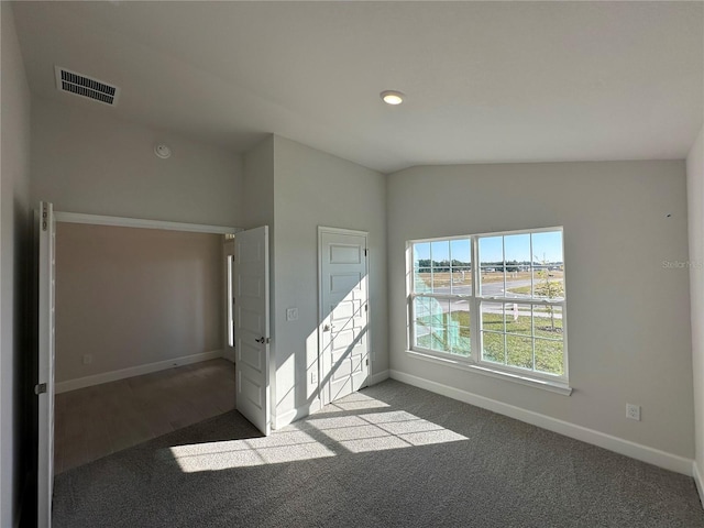 empty room featuring vaulted ceiling, carpet, visible vents, and baseboards